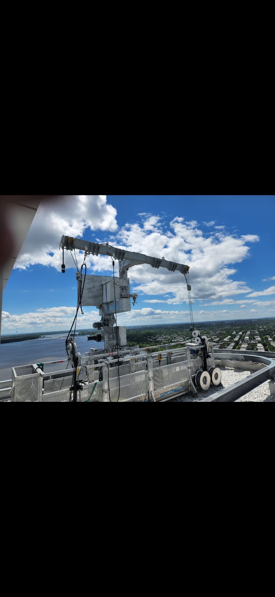 Vue en plongée d'une structure équipée d'un radar ou d'une antenne, sur fond de ciel bleu nuageux.