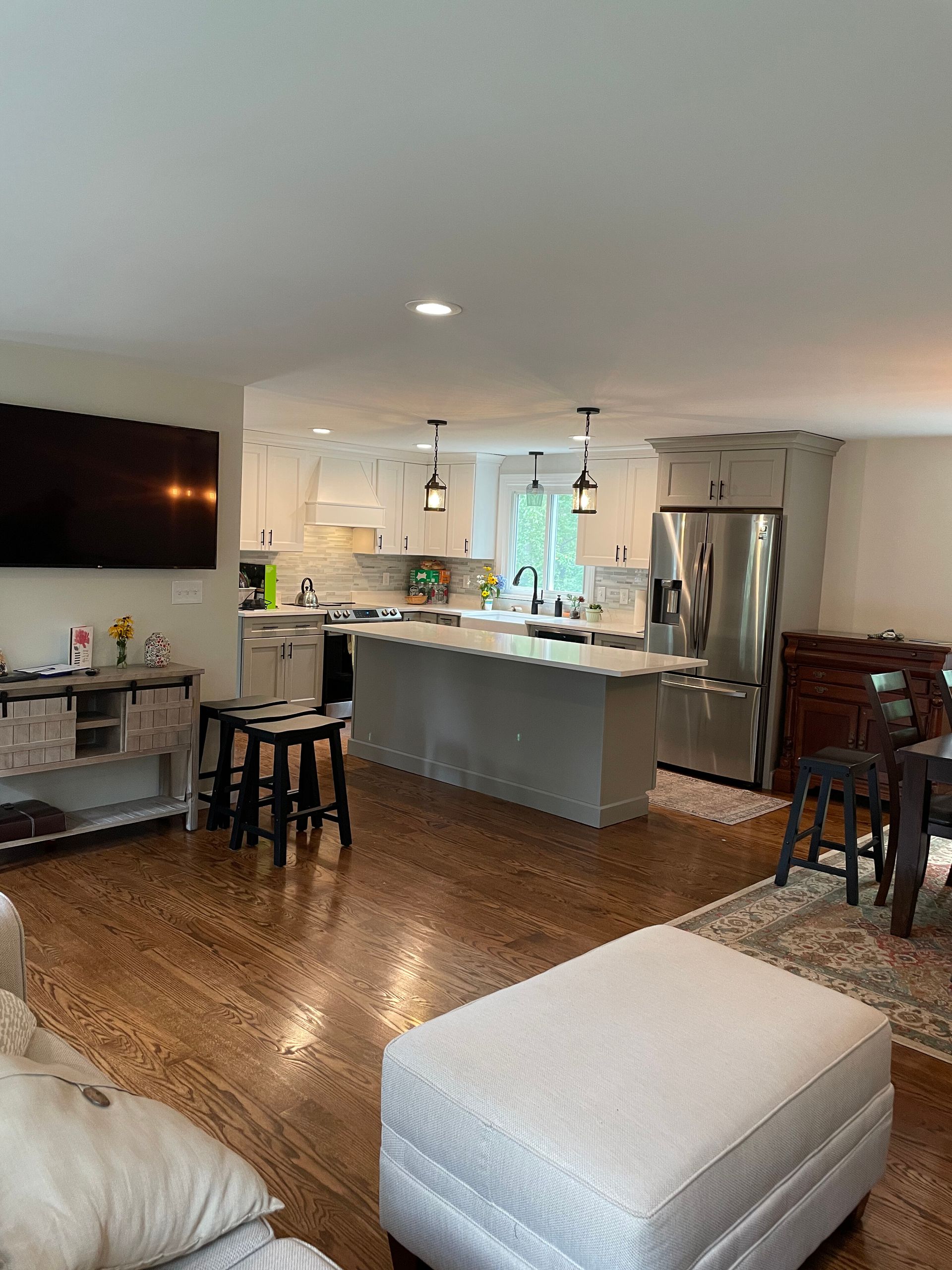 A spacious open-concept kitchen with white cabinets, a central island, stainless appliances, and hardwood floors.