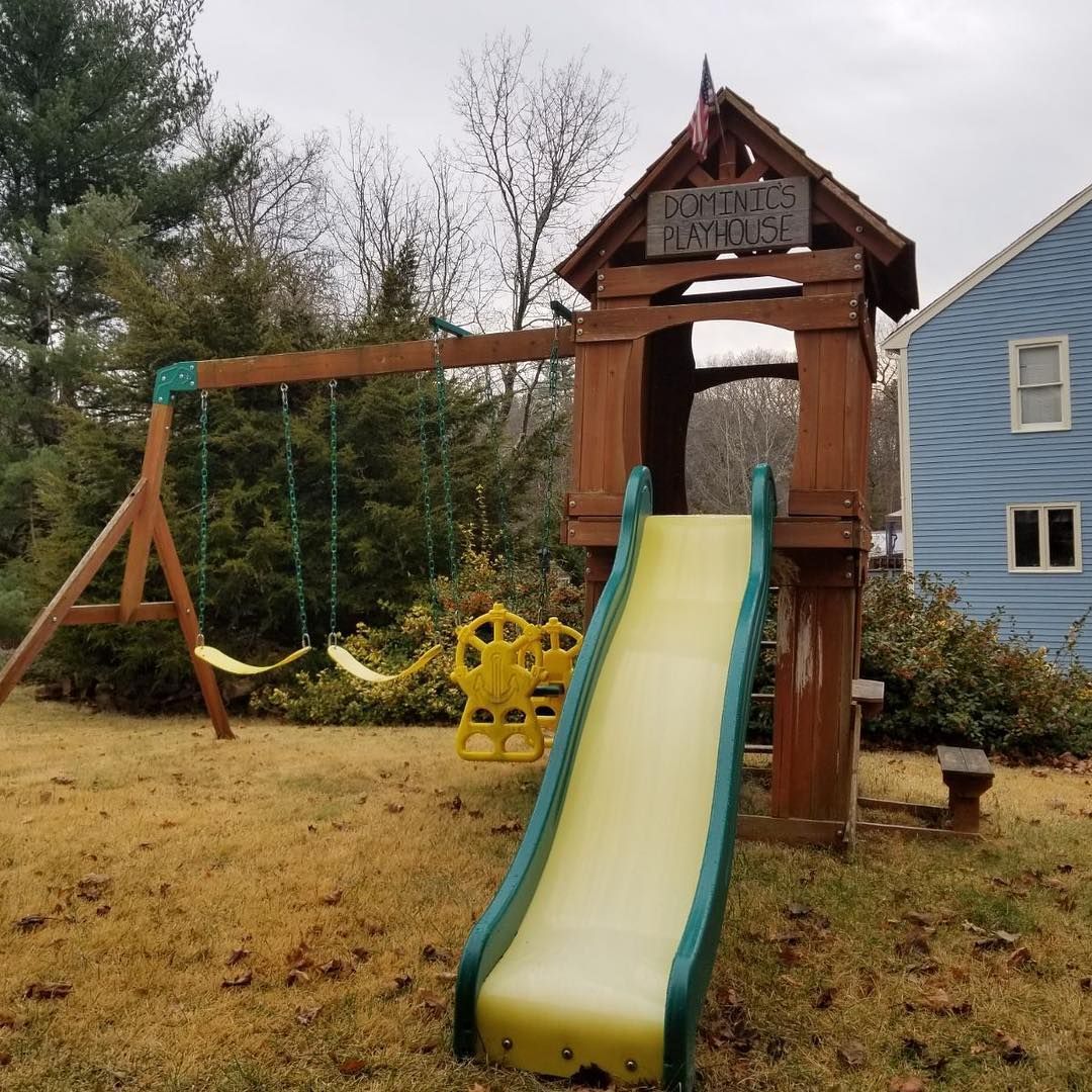 A wooden swing set with a slide and a sign that says outdoor adventures