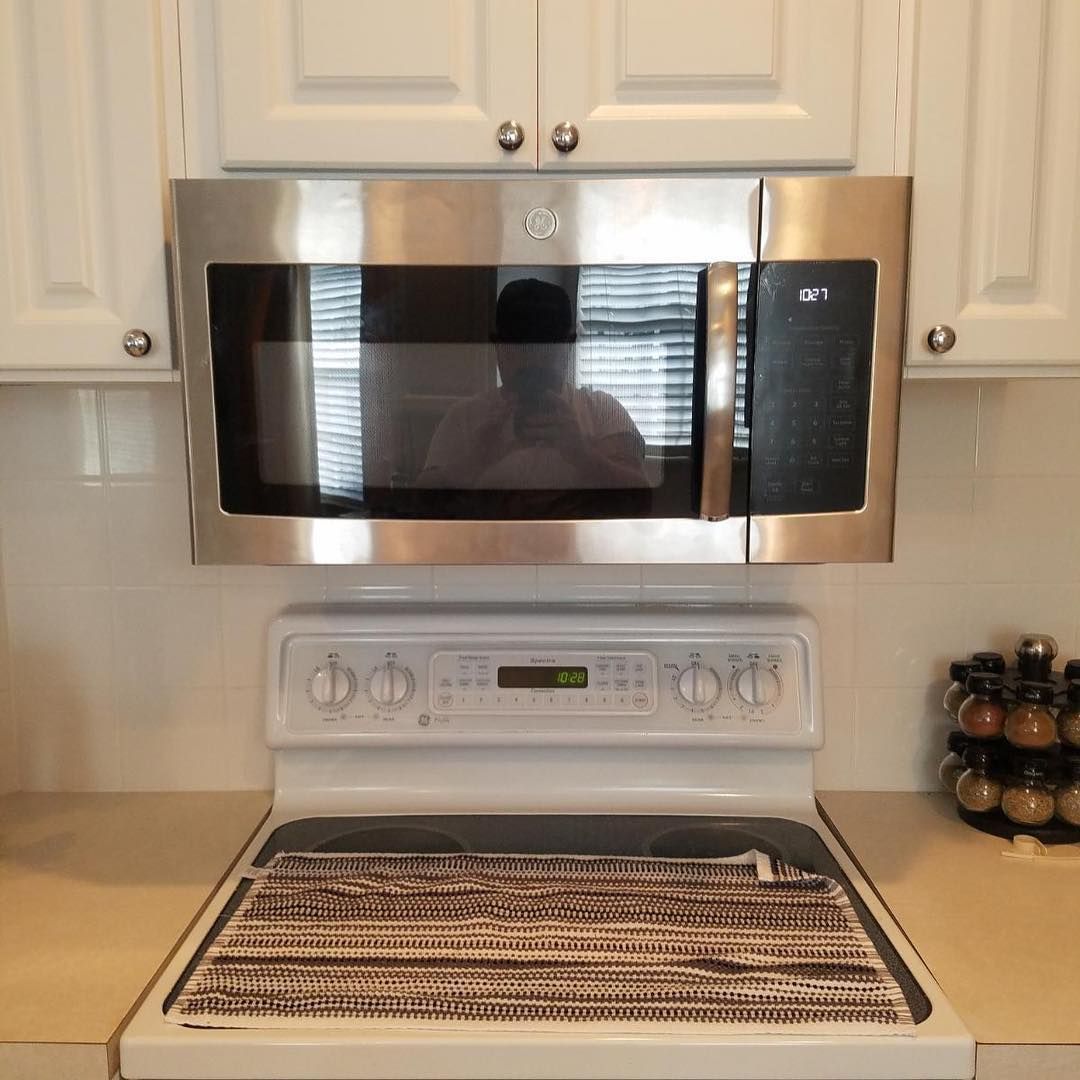 A stove top oven with a stainless steel microwave above it