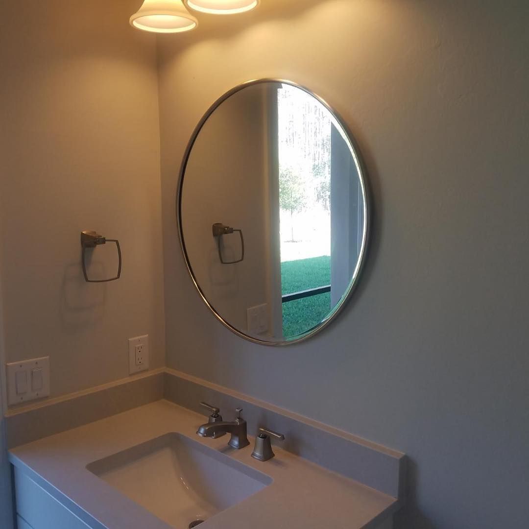 A bathroom sink with a round mirror above it