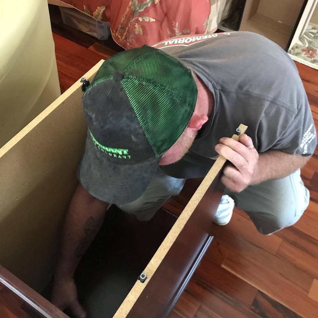 A man wearing a green hat is working on a cabinet