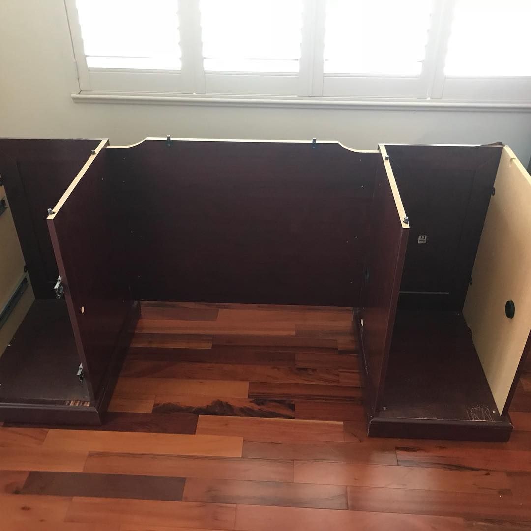 A wooden cabinet is sitting on a wooden floor next to a window.