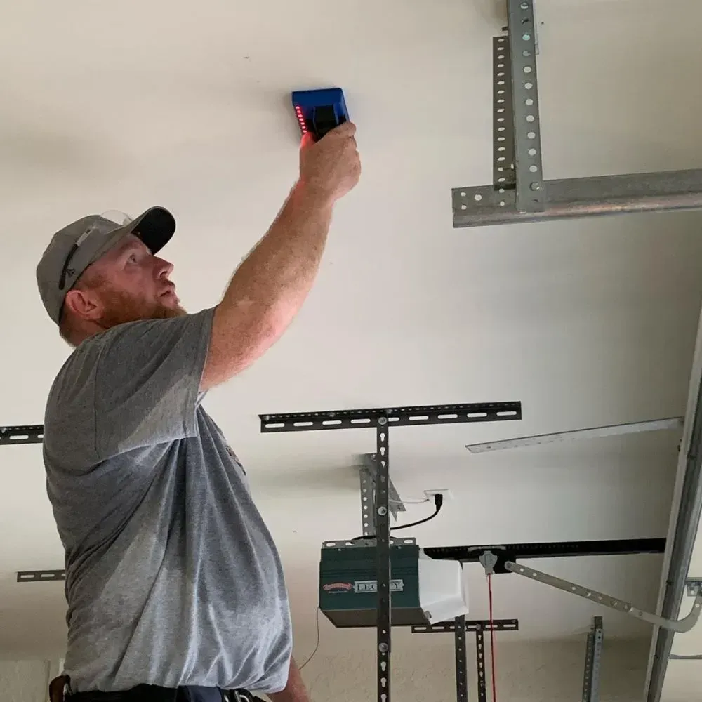 A man is measuring the ceiling of a garage with a tape measure.