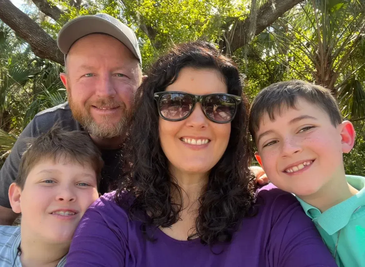 A family posing for a picture with two boys and a woman wearing sunglasses.