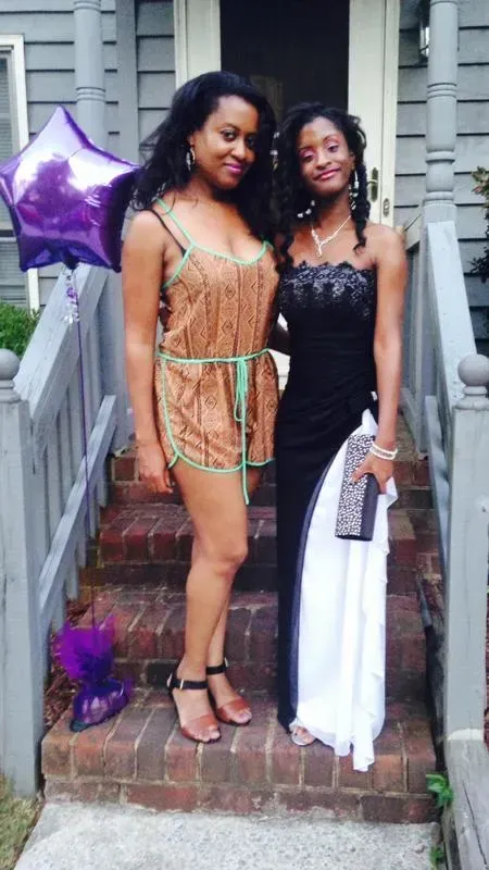 Two women are posing for a picture on the steps of a house