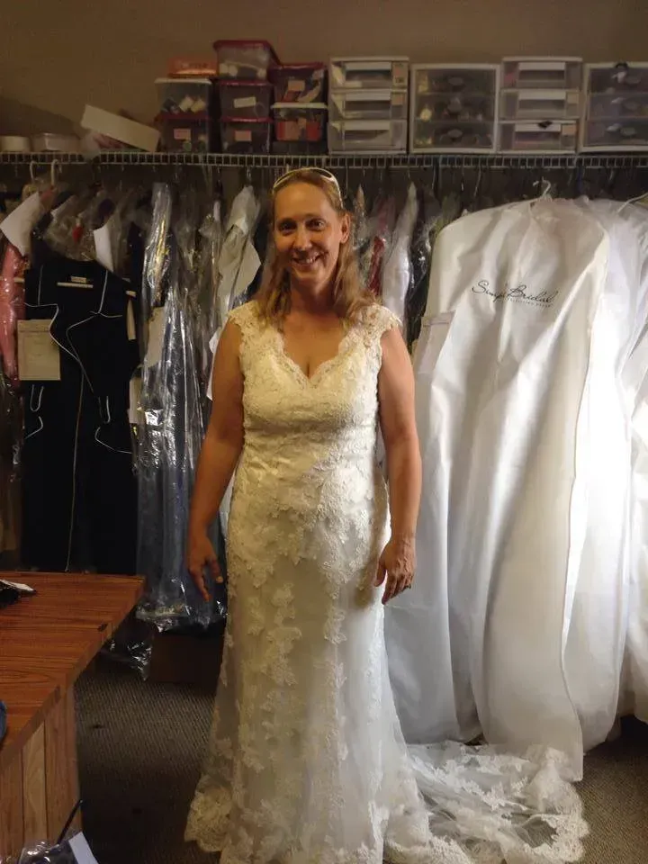 A woman in a wedding dress is standing in front of a closet full of wedding dresses.