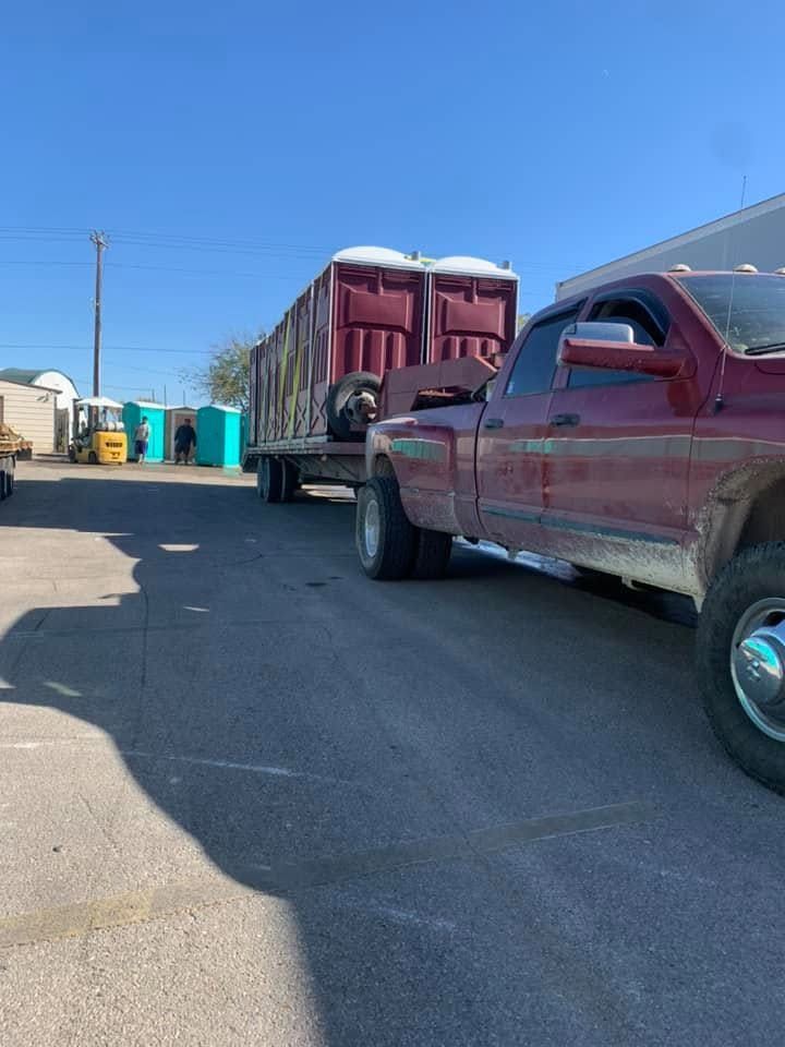 Red pickup truck hauling a flatbed trailer on a sunny industrial lot