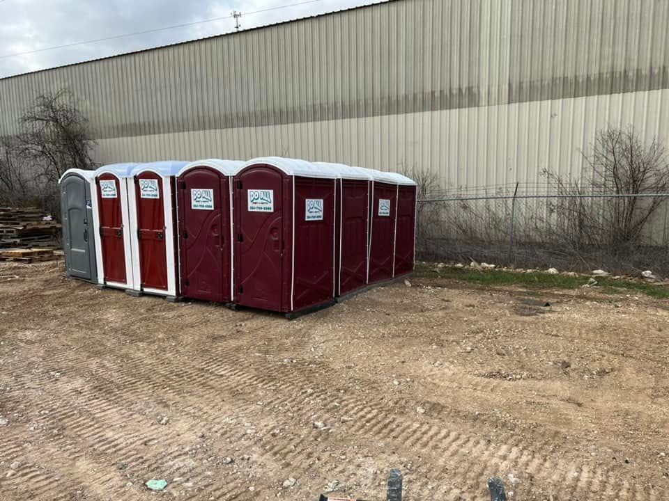 Portable toilets lined up beside a warehouse on a gravel lot