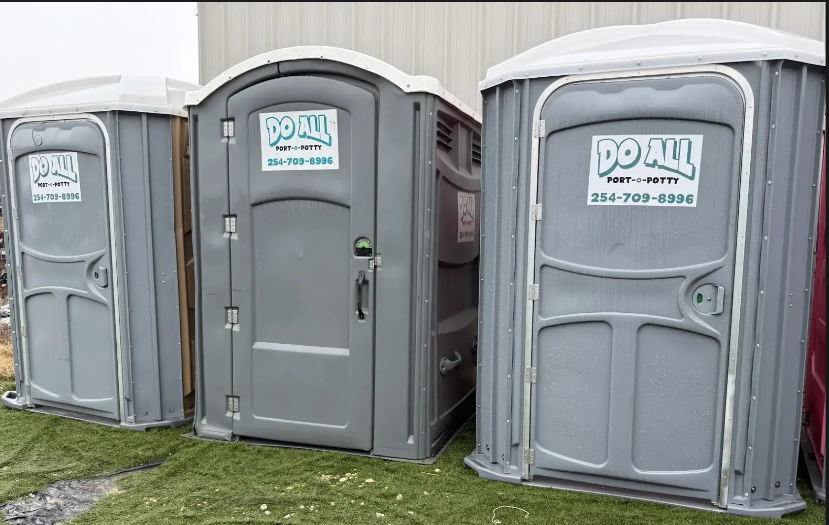 Red portable toilet with patriotic red, white, and blue rocket decoration on grass