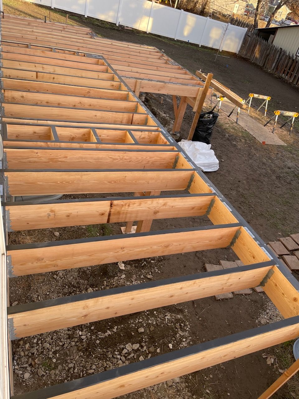 Exposed wooden floor joists over a gravel foundation at a construction site