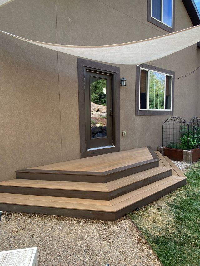 Stucco house entry with curved concrete steps, dark front door, window, and small yard path