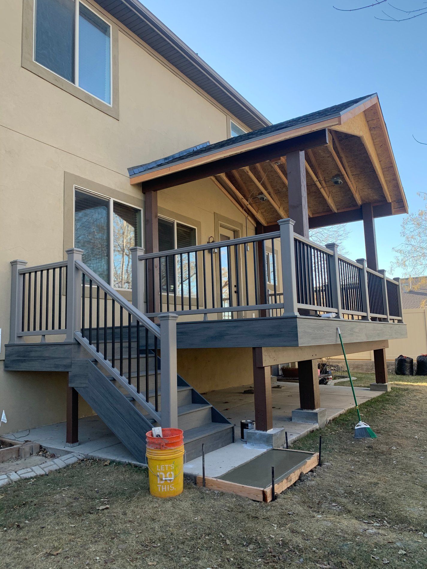 Wooden deck and stairs on a beige house with a covered porch and slanted roof
