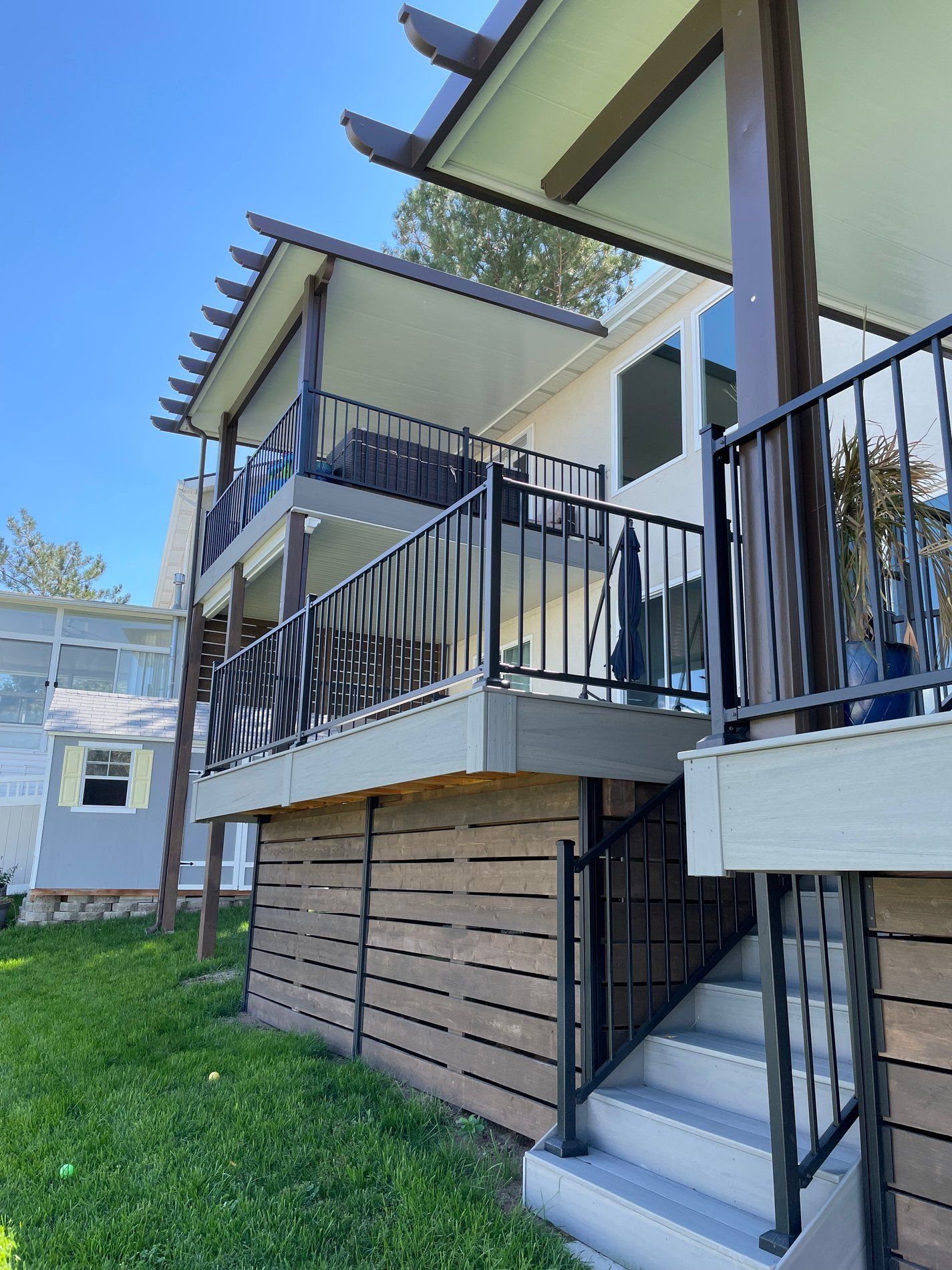 Exterior of a raised house with white siding, black railings, and stairs leading to a small porch