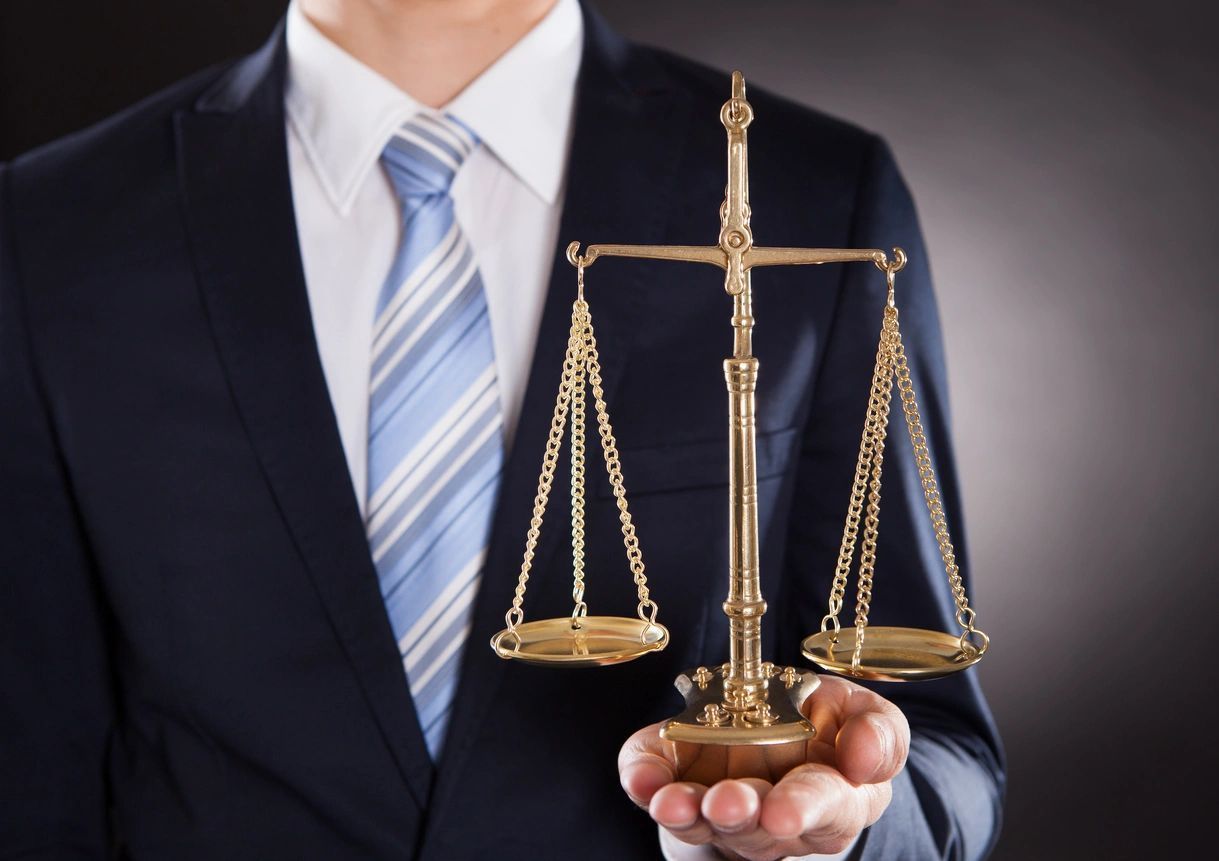 a man in a suit and tie is holding a scale of justice