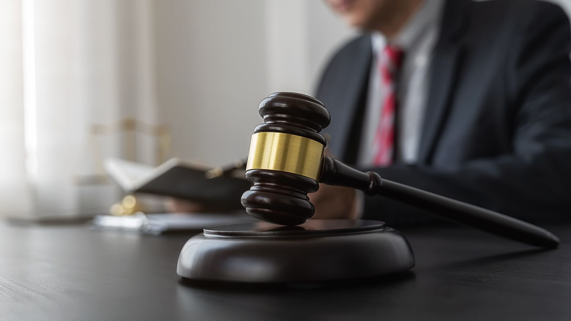 a man in a suit and tie is sitting at a table with a wooden gavel