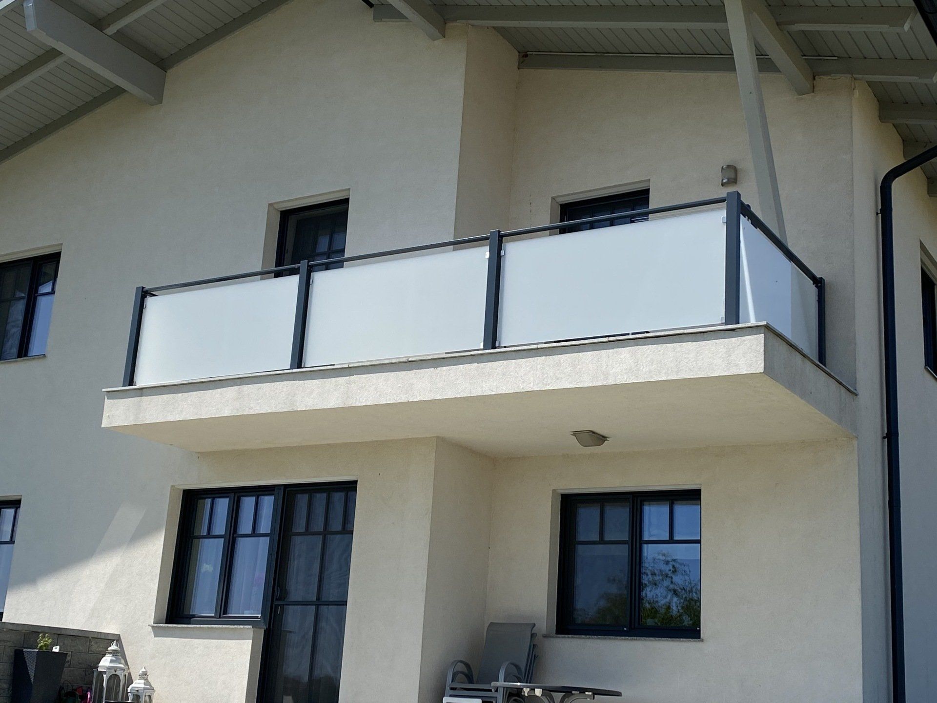Ein weißes Haus mit Balkon und schwarzen Fenstern