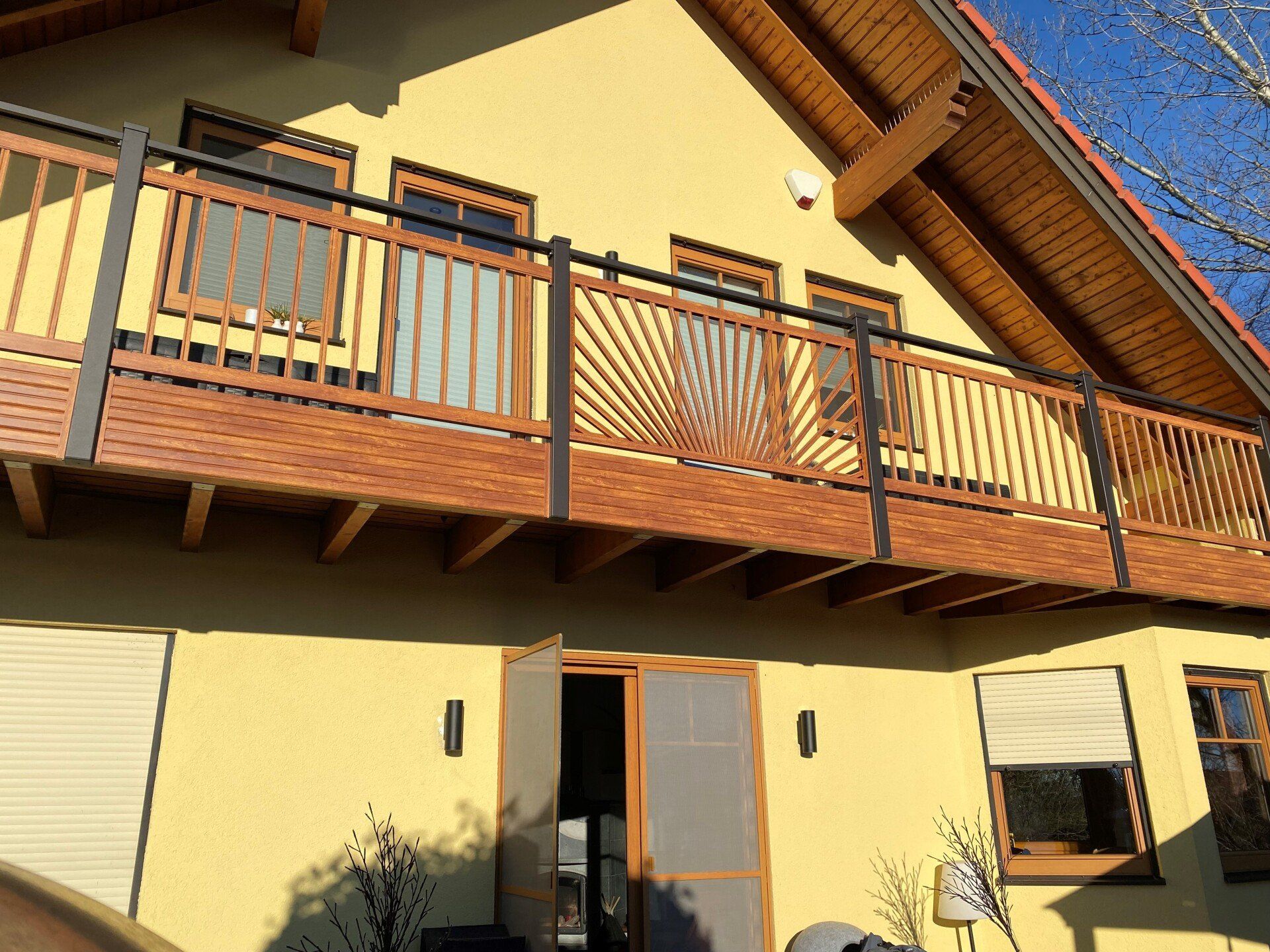 Ein gelbes Haus mit einem Holzbalkon im zweiten Stock