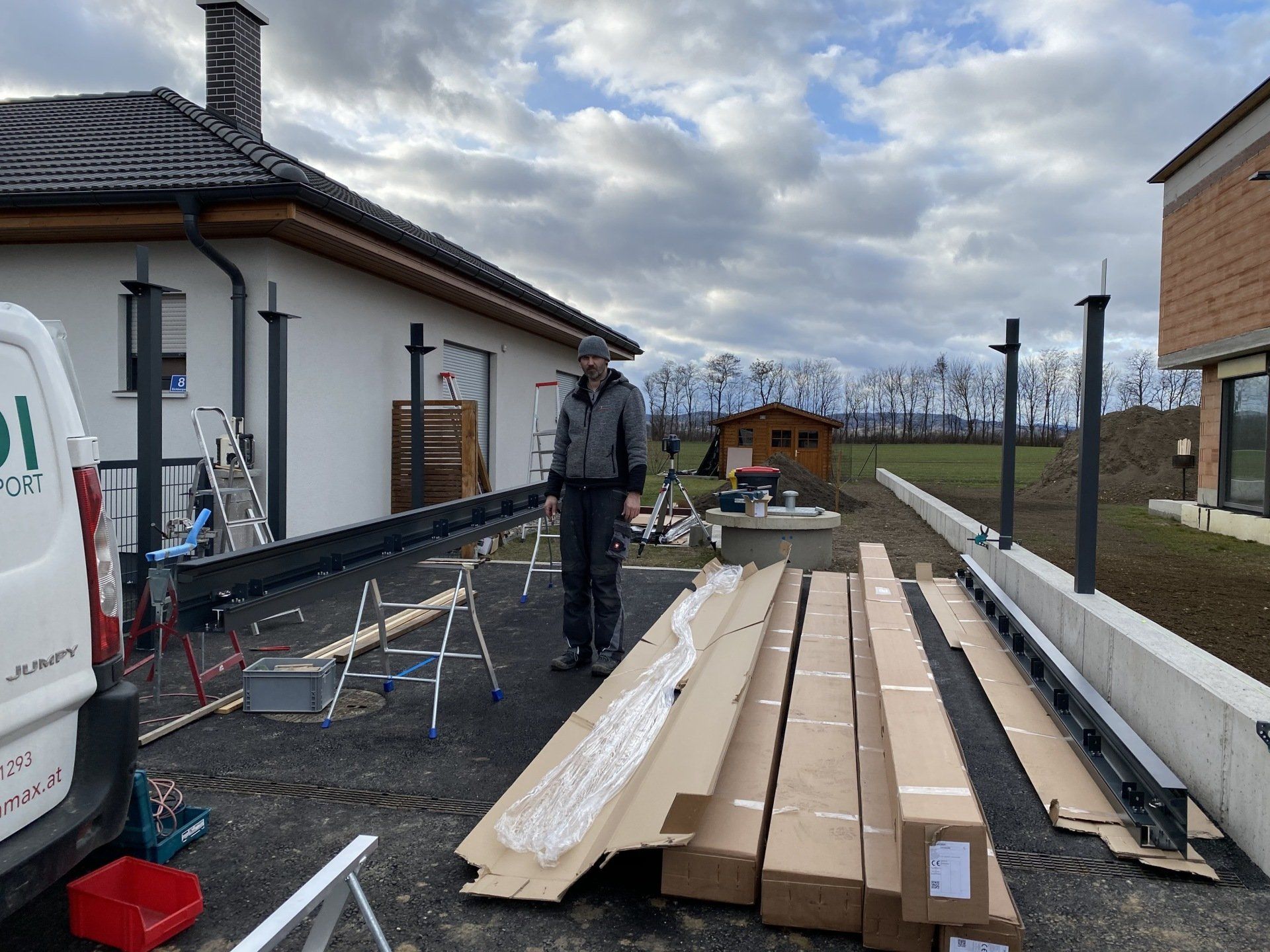 Ein Mann steht vor einem Haus, das von Pappkartons umgeben ist.