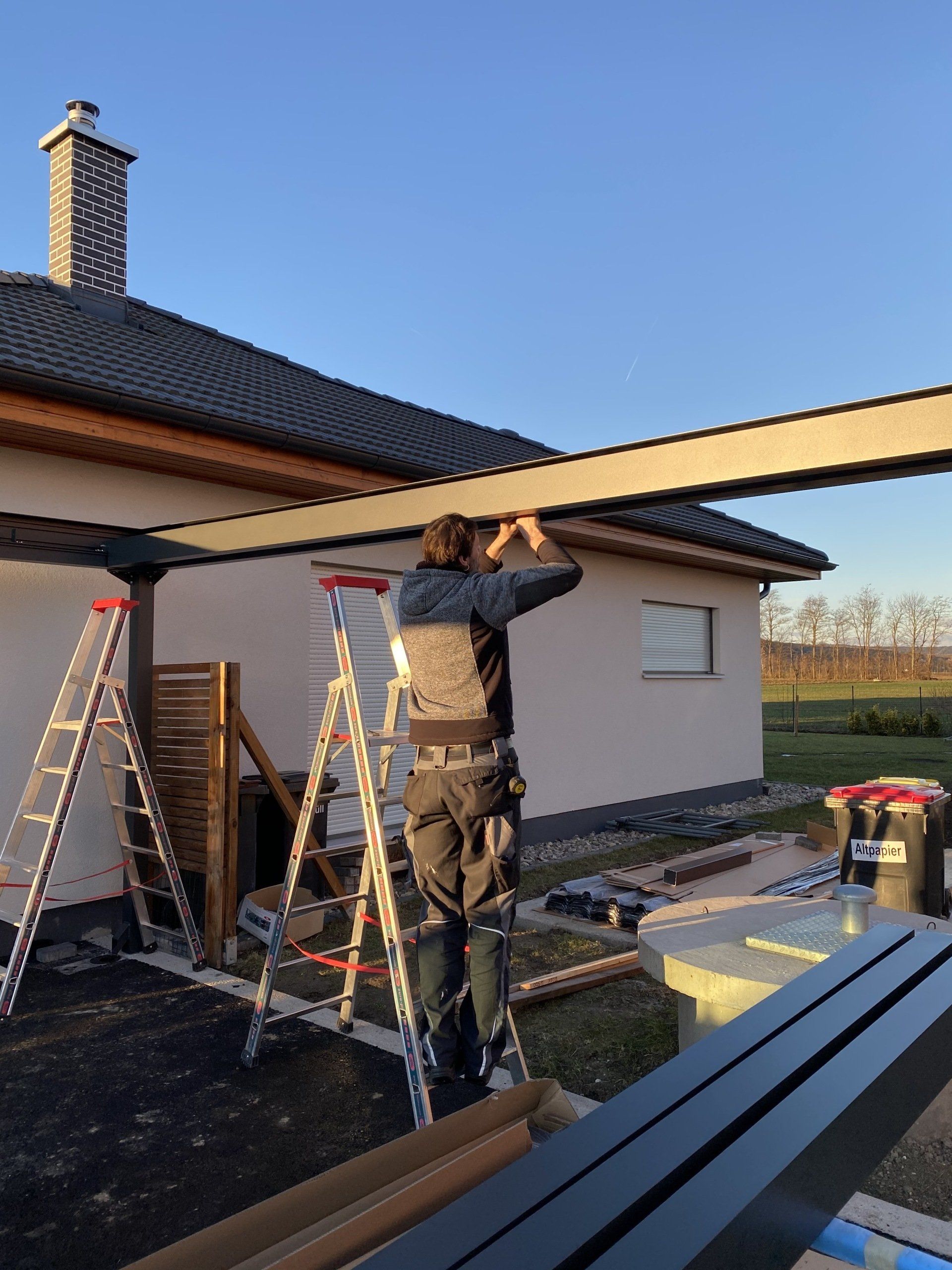 Ein Mann steht auf einer Leiter vor einem Haus