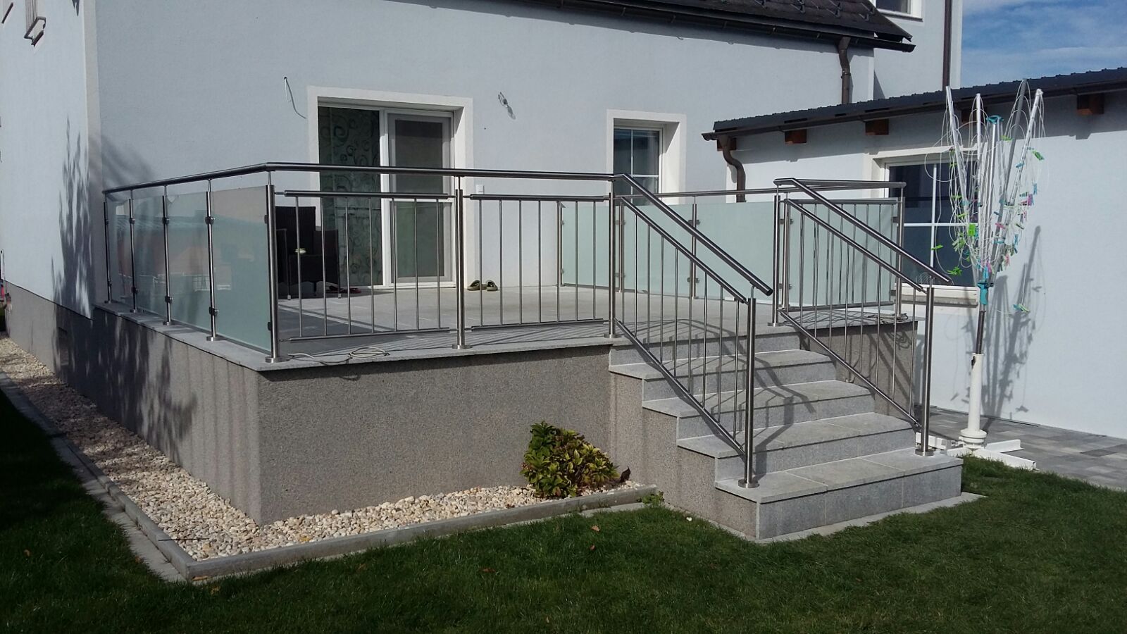 Ein weißes Haus mit einem Balkon und einer Treppe davor.