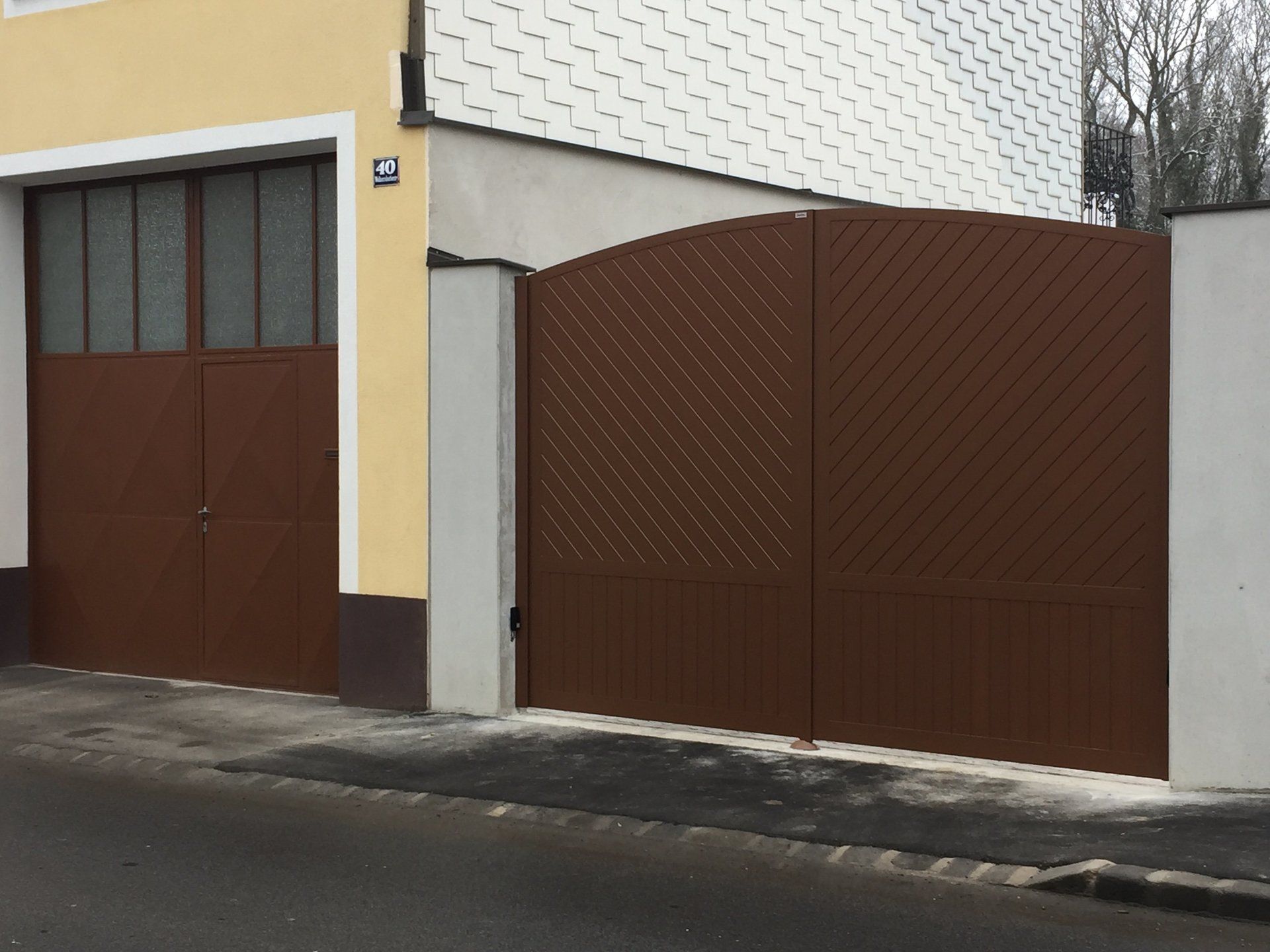 Ein braunes Garagentor befindet sich neben einem gelben Gebäude