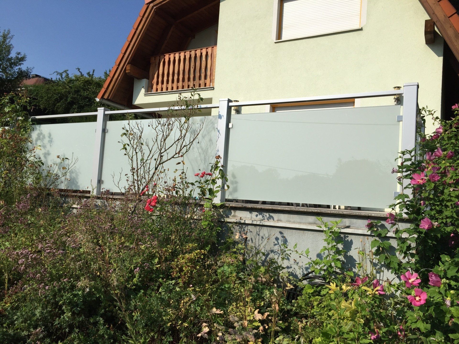 Ein Haus mit einem Zaun und Blumen davor