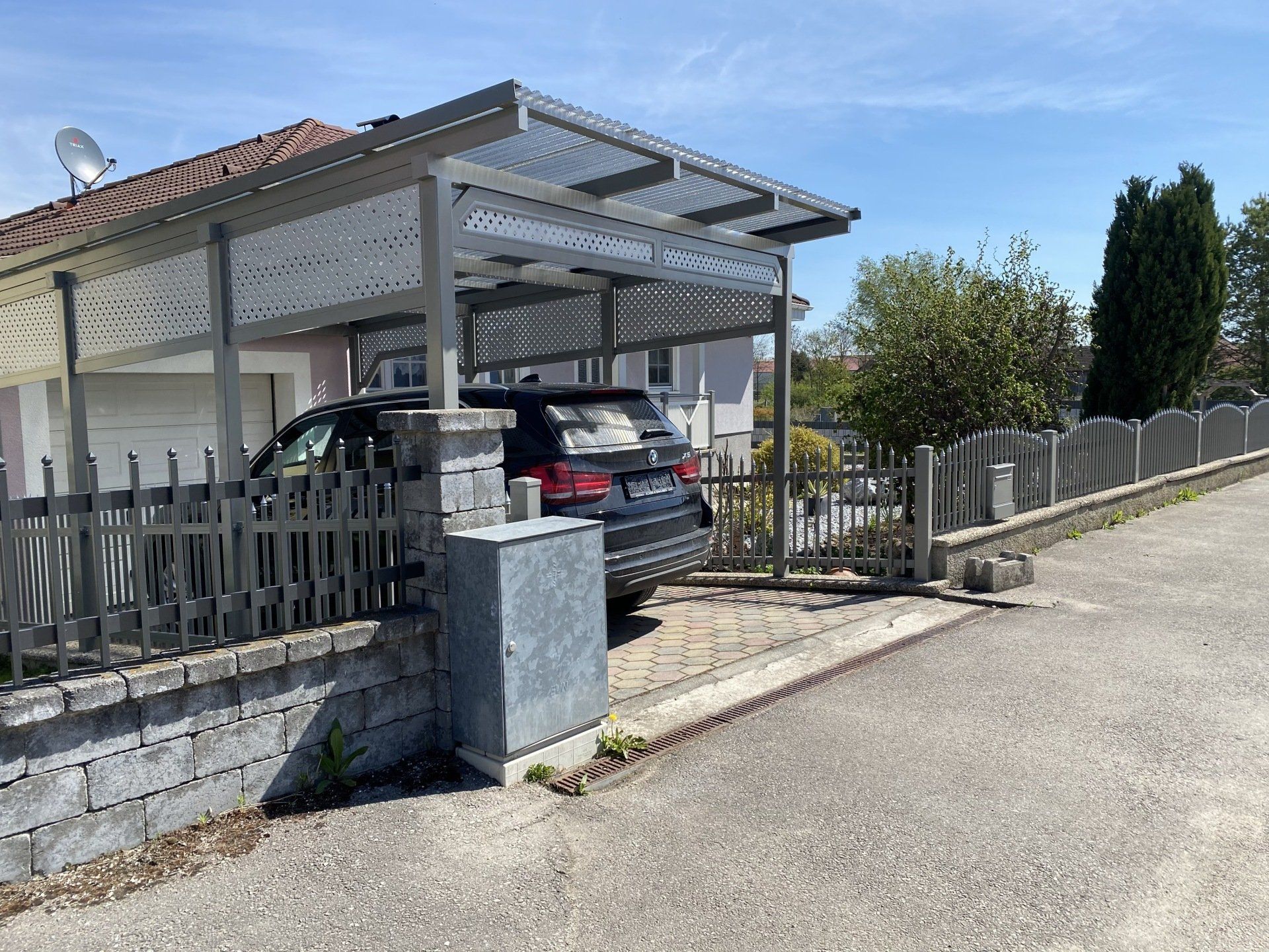 Ein Auto ist unter einem Vordach vor einem Haus geparkt.