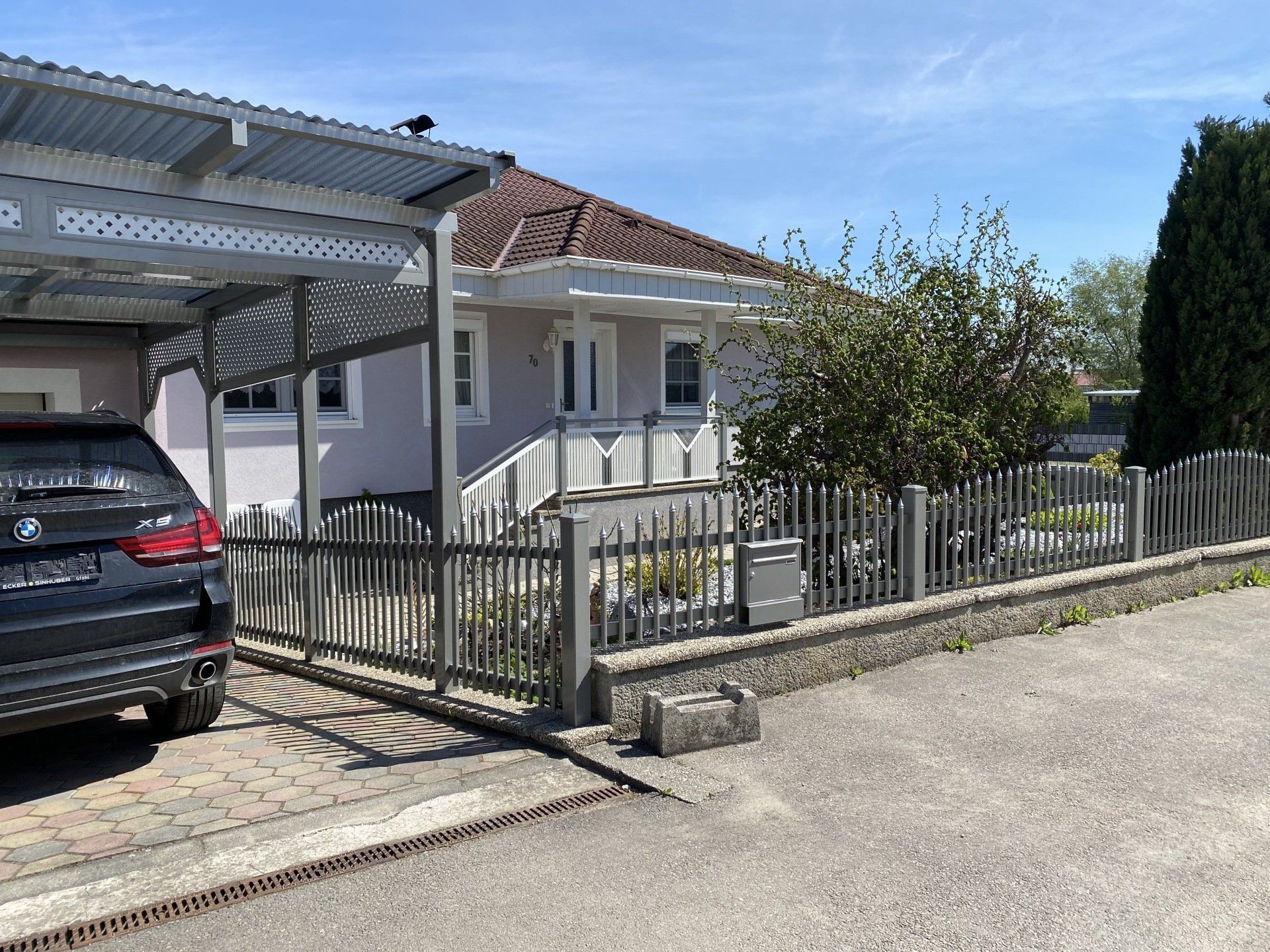 Vor einem Haus mit Carport steht ein Auto.