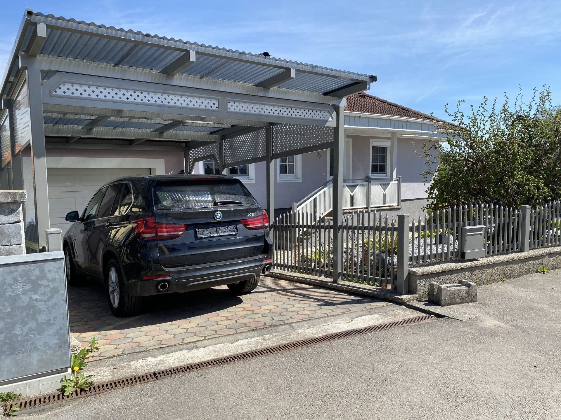 Ein Auto ist unter einem Carport vor einem Haus geparkt.