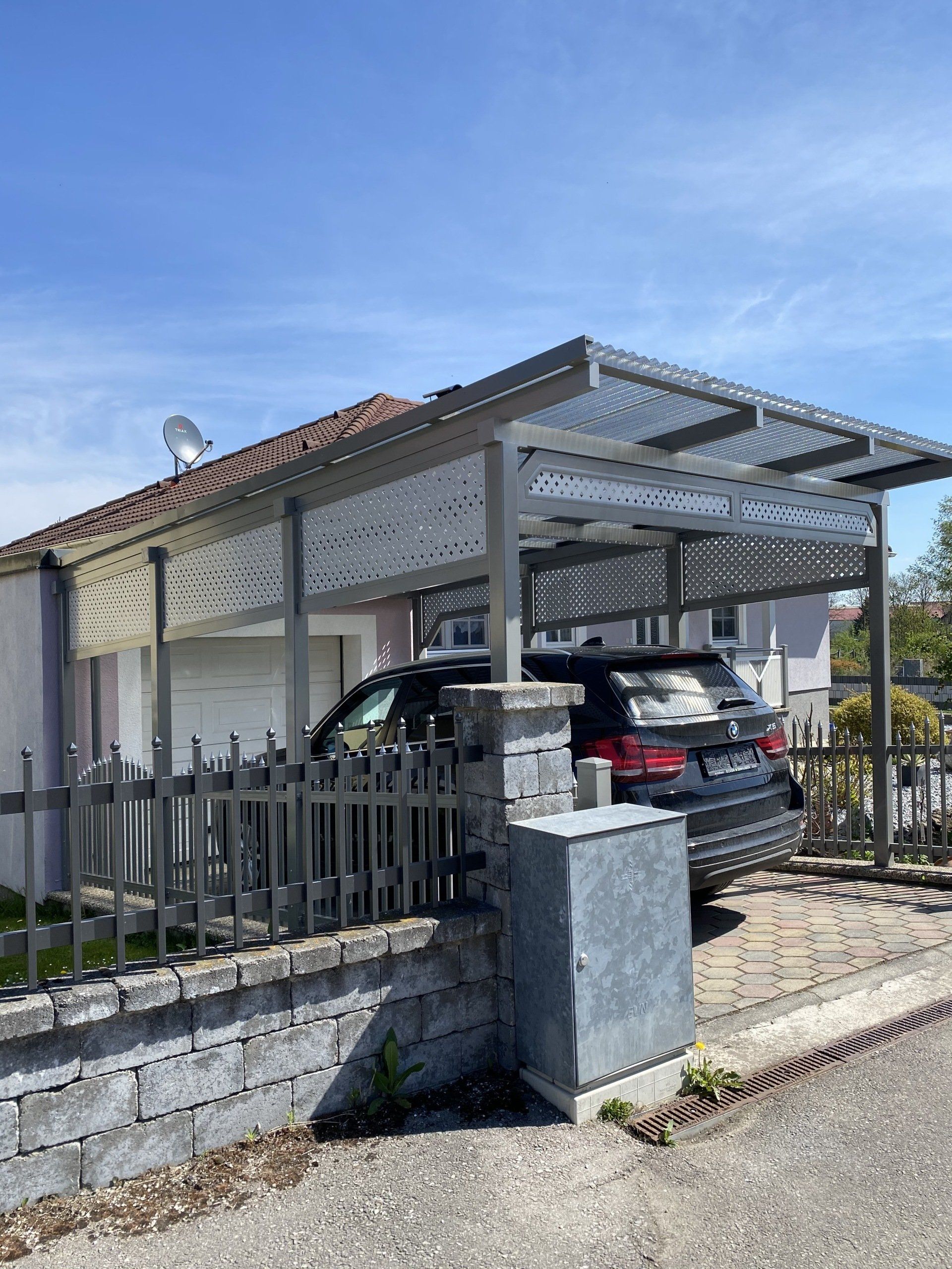 Ein Auto ist unter einem Vordach vor einem Haus geparkt.