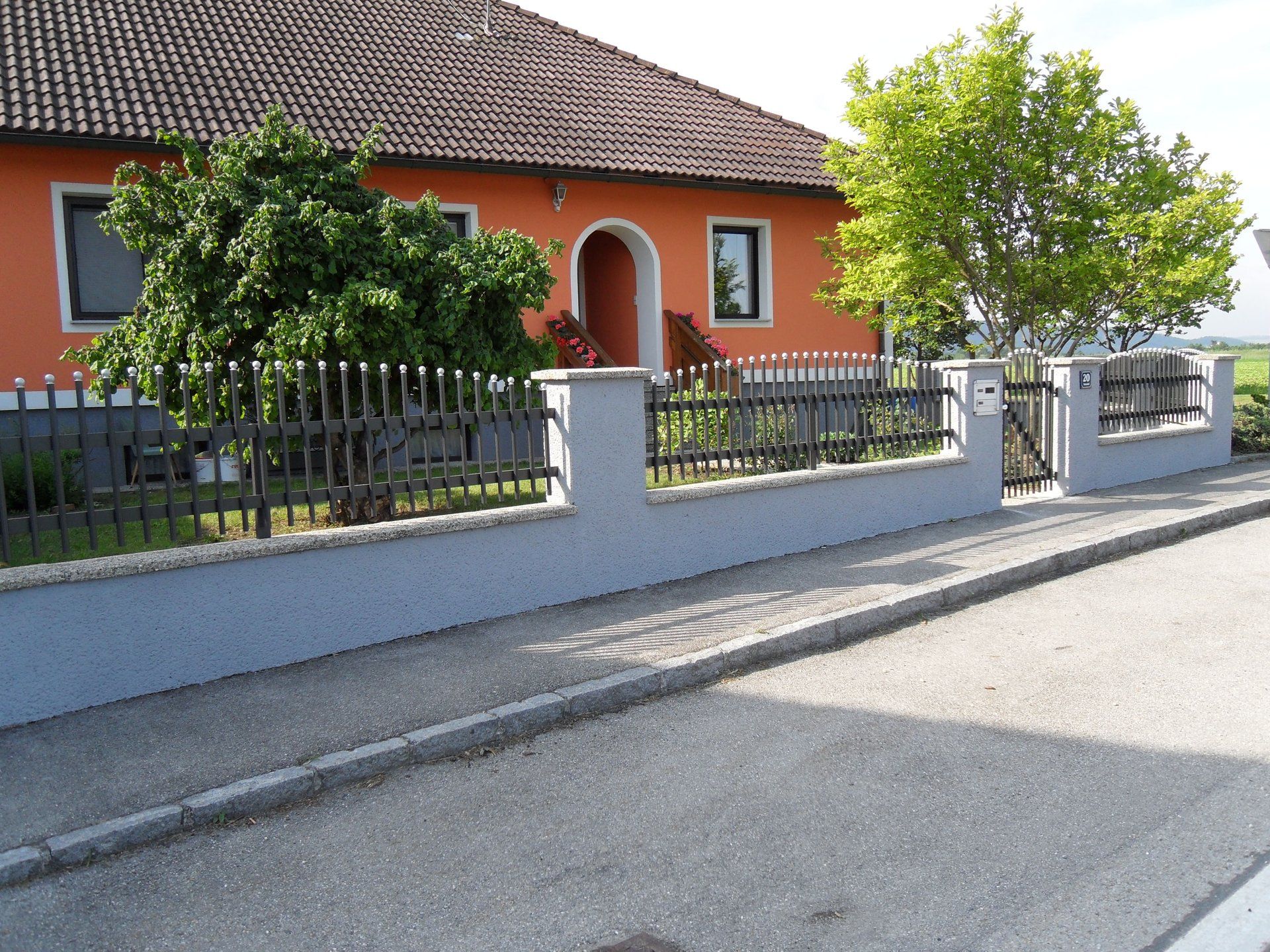 Ein Haus mit einem Zaun und einem Baum davor