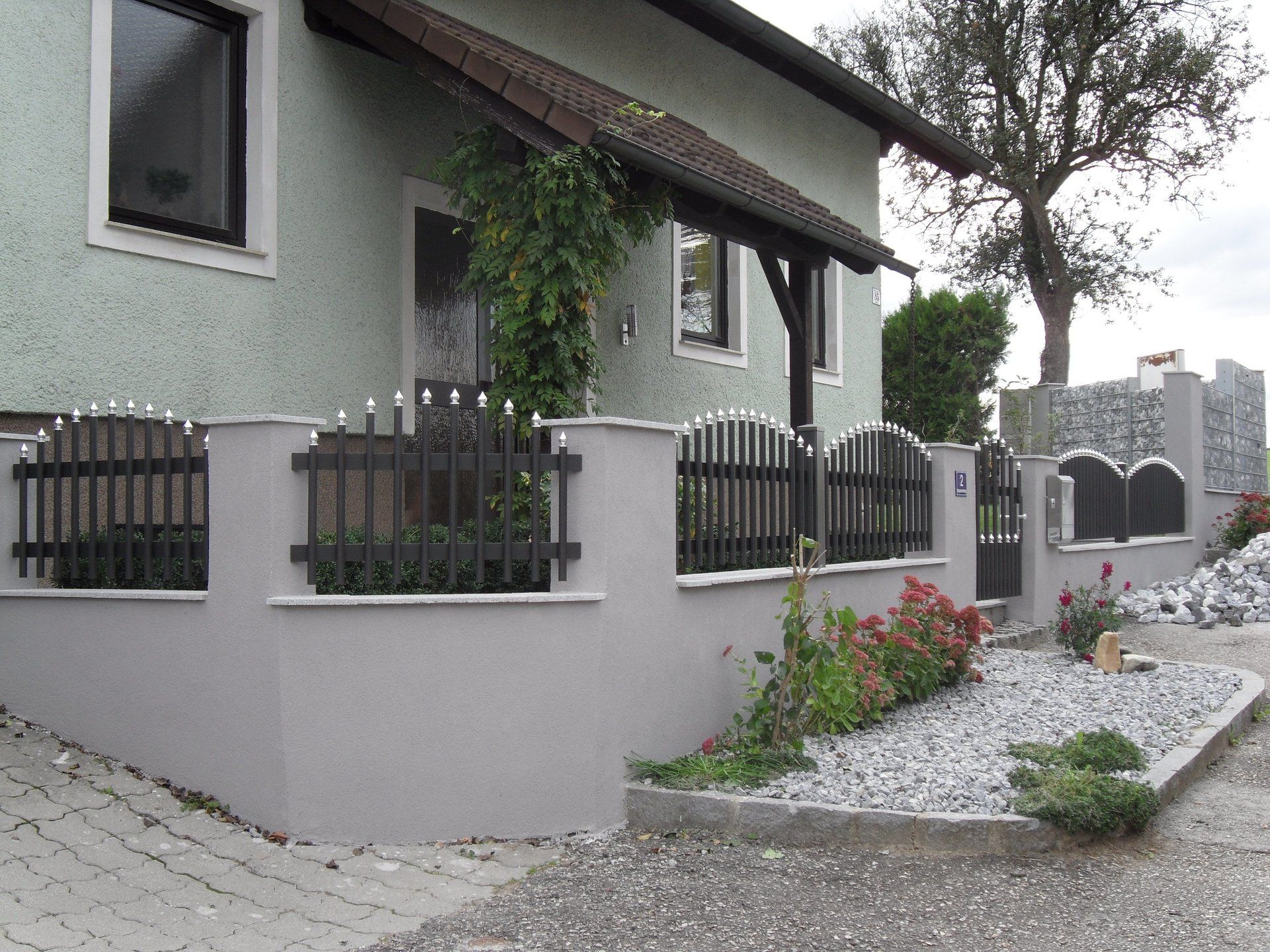 Ein Haus mit einem schwarzen Zaun und einer Kiesauffahrt