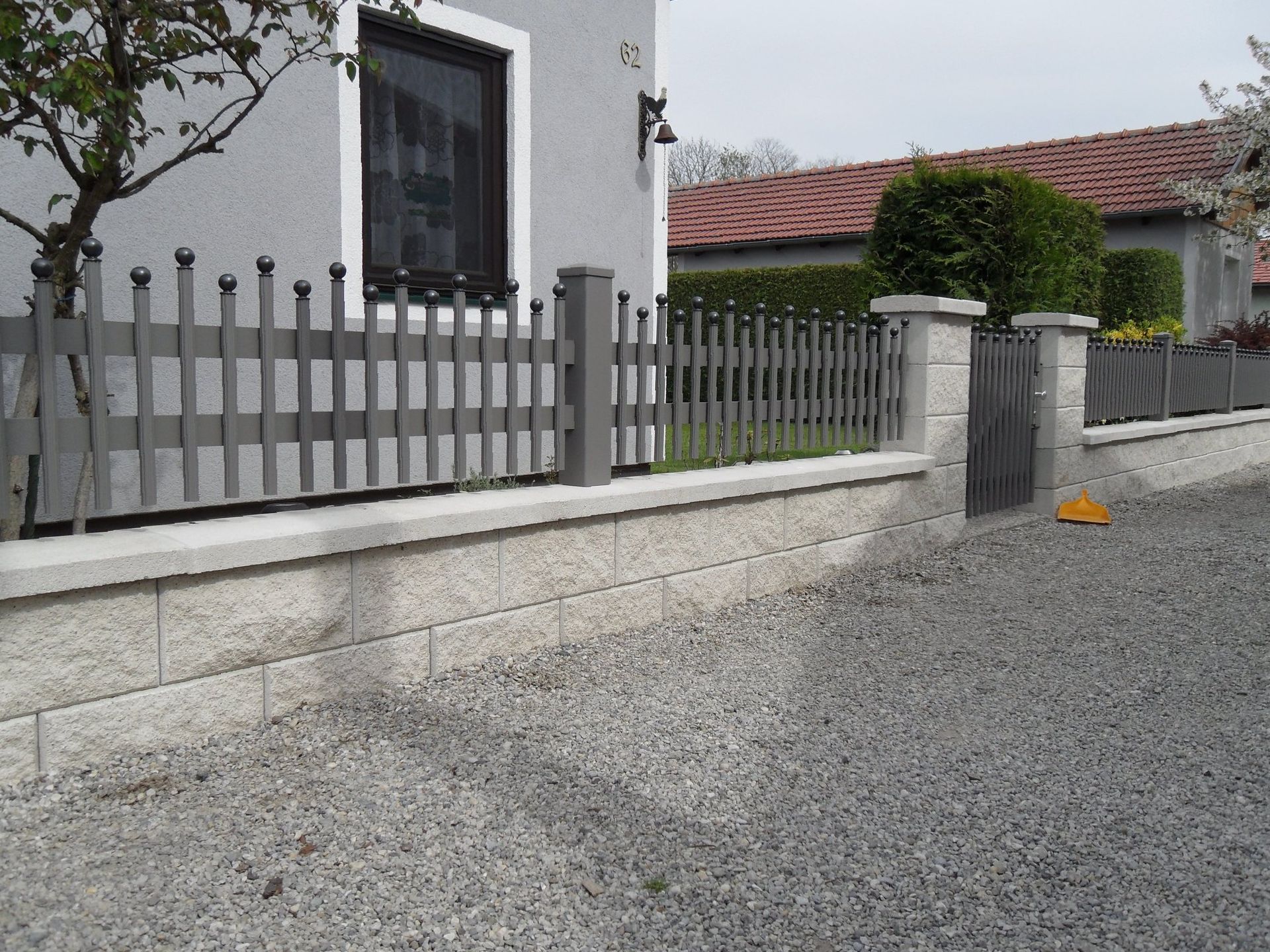 Ein Zaun umgibt eine Kiesauffahrt vor einem Haus