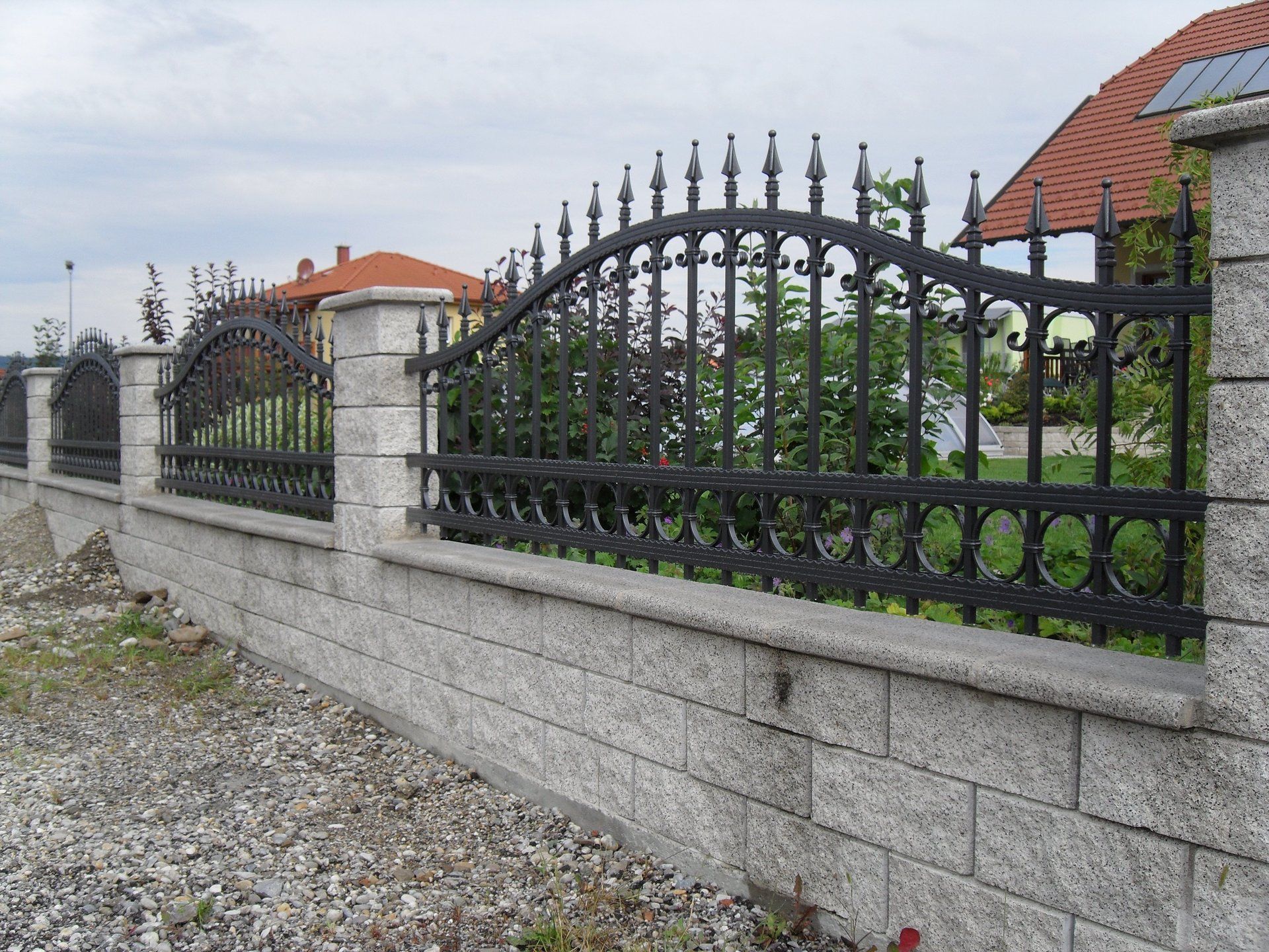 Eine Backsteinmauer, die von einem schmiedeeisernen Zaun umgeben ist
