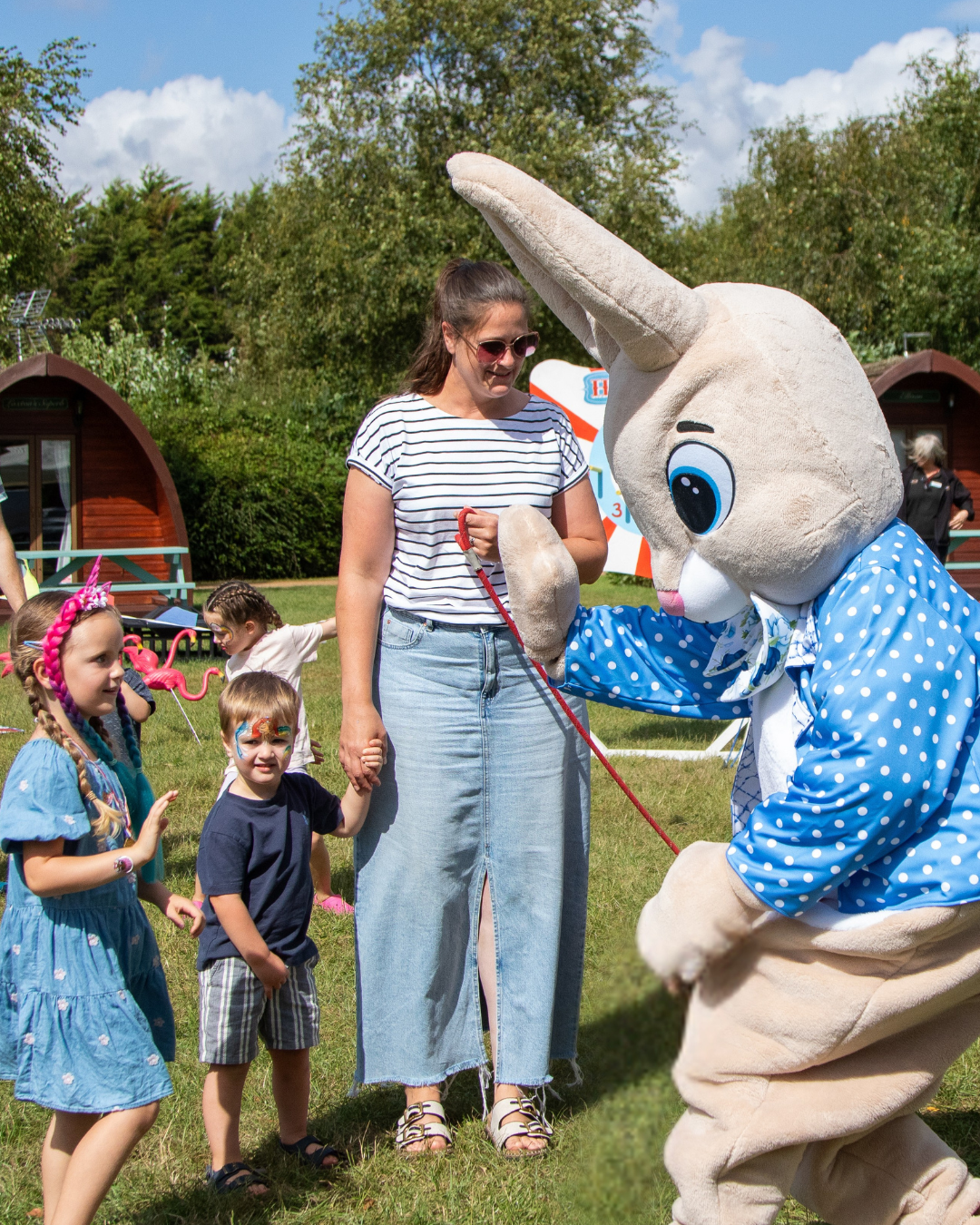 A family meeting a character costume rabbit with a blue and white polka dot jacket