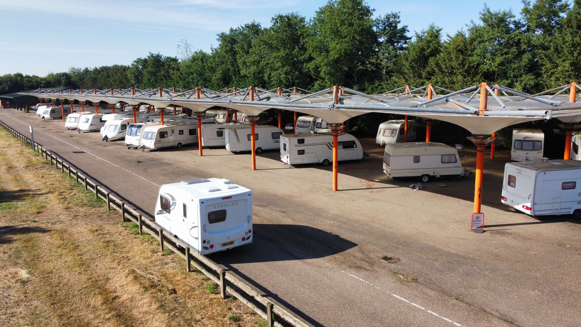 Row of parked caravans under solar panel canopies. Outdoor setting.