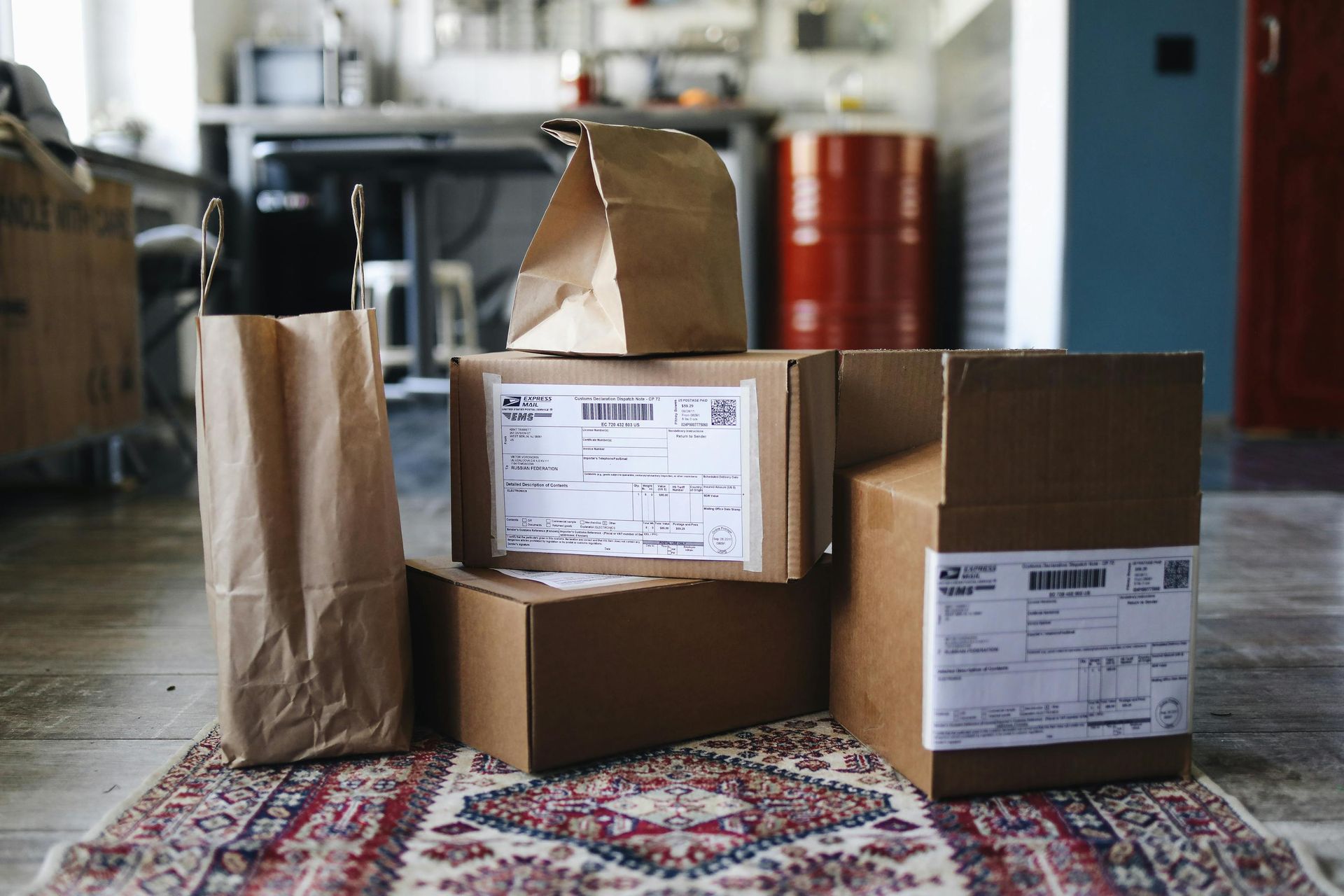 A stack of boxes and bags are sitting on a rug on the floor.