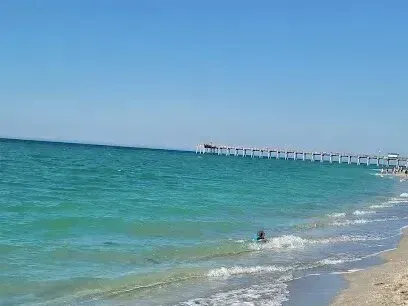 Hvac-Contractor-Bradenton-Ocean view: turquoise water, sandy beach, pier in distance, clear blue sky.