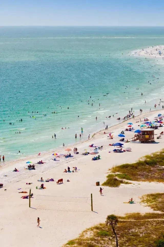 HVAC-contactor-Beach scene with turquoise water, white sand, and numerous people enjoying the sun and water.