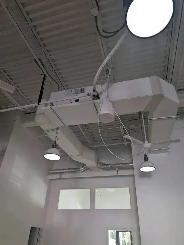 Hvac-Contractor-Bradenton-White ceiling with industrial-style lights, an air duct system, and windows in a building's interior.