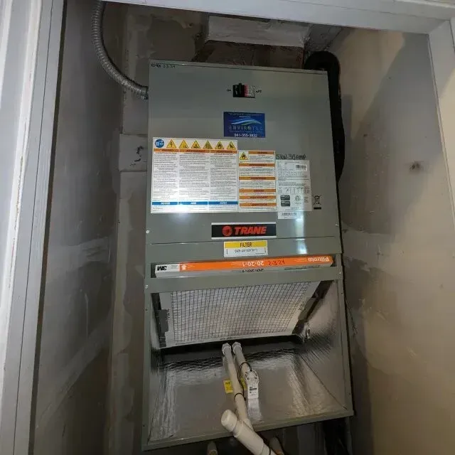 Hvac-Contractor-Bradenton-HVAC unit, Trane brand, in a closet. Filter visible. Warning labels on the unit.