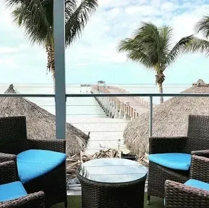 Hvac-Contractor-Bradenton-A beach patio with wicker furniture and a view of a pier and ocean under palm trees.