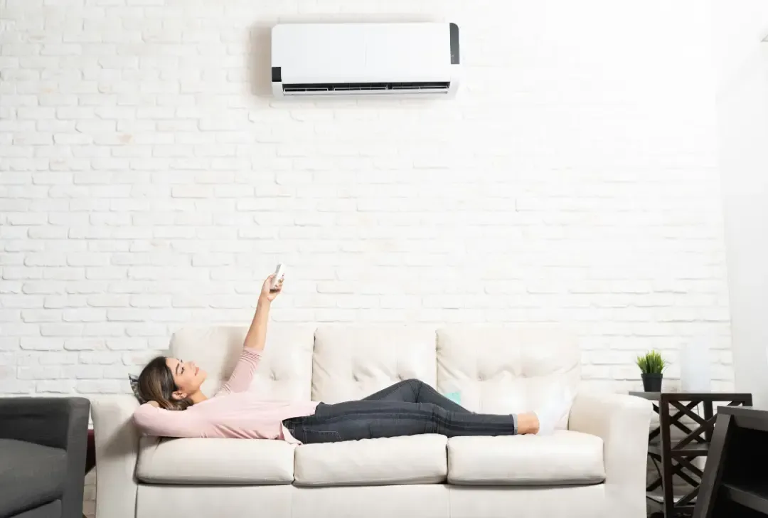 A woman is laying on a couch holding a remote control.