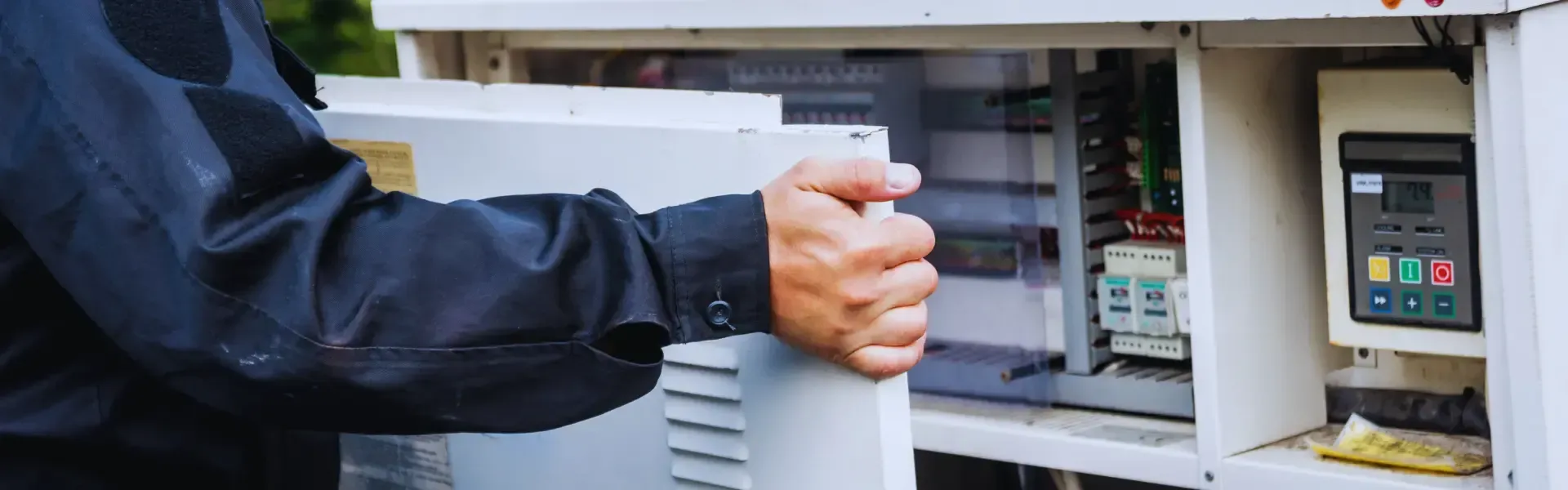 A man is holding a piece of paper in front of a electrical box.