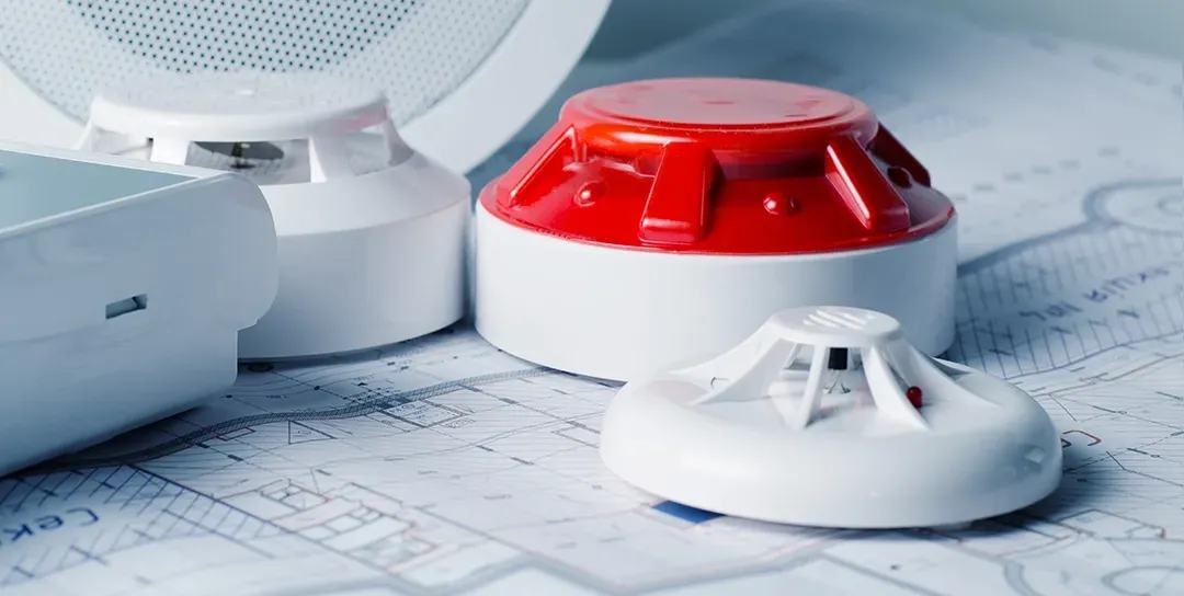 A group of fire alarms are sitting on top of a blueprint.