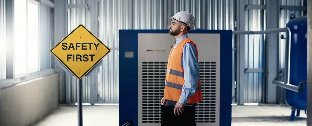 A man is standing in front of a safety first sign.
