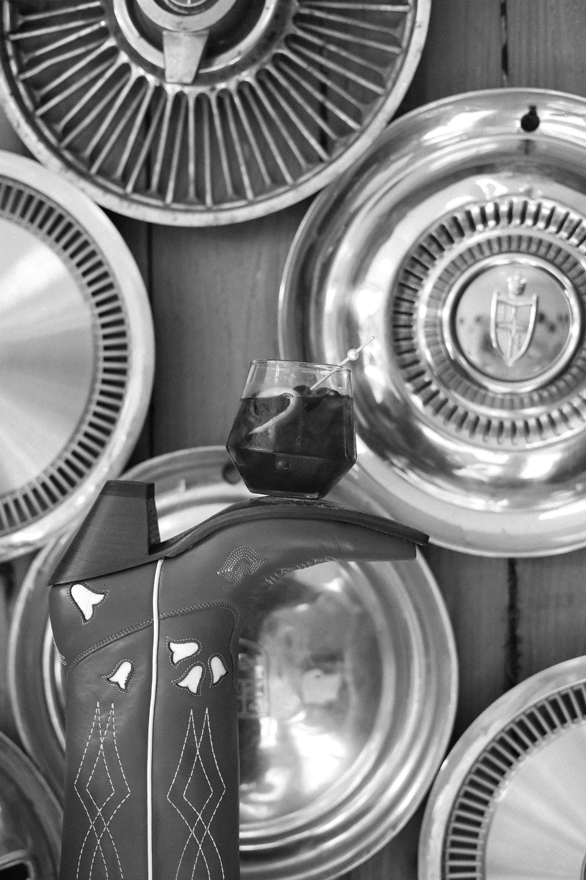 Decorative glass vase with a dark vase top in front of shiny metallic wheel rims