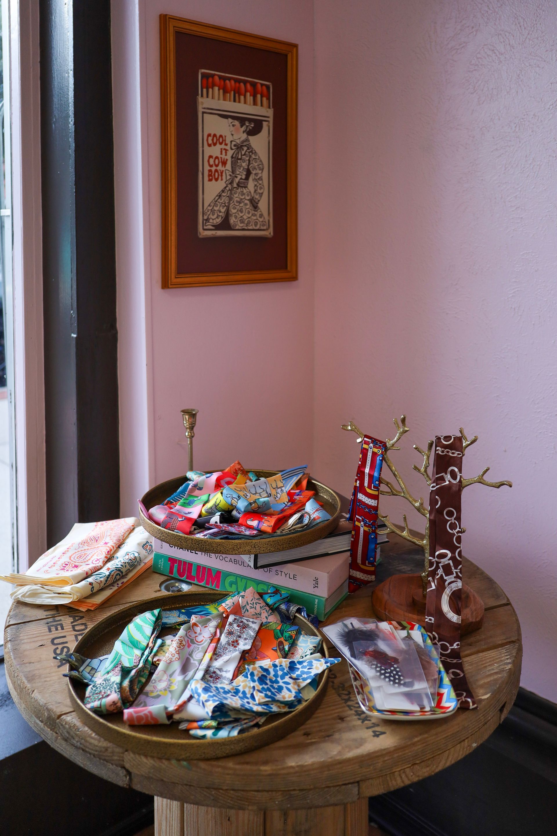 Round table with colorful wrapped candies and snacks in a corner beside a framed wall hanging.