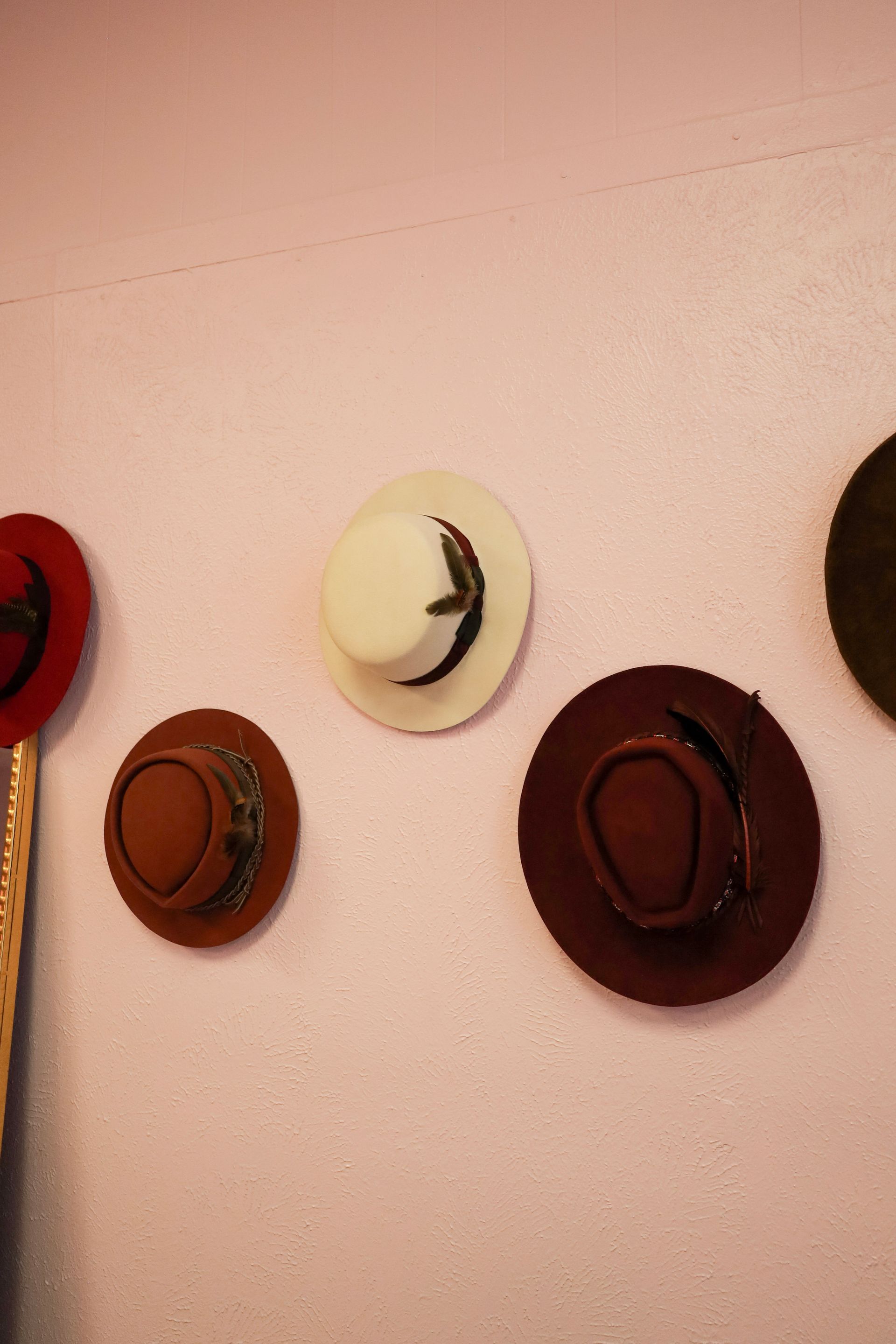 Wall with four colorful hats or wall hooks arranged in a row on a pink background